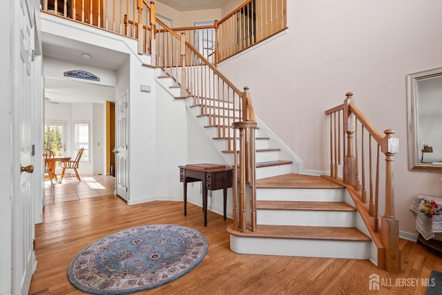 staircase with wood-type flooring and a high ceiling