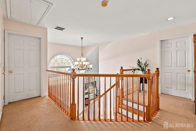 hallway featuring light colored carpet and a chandelier