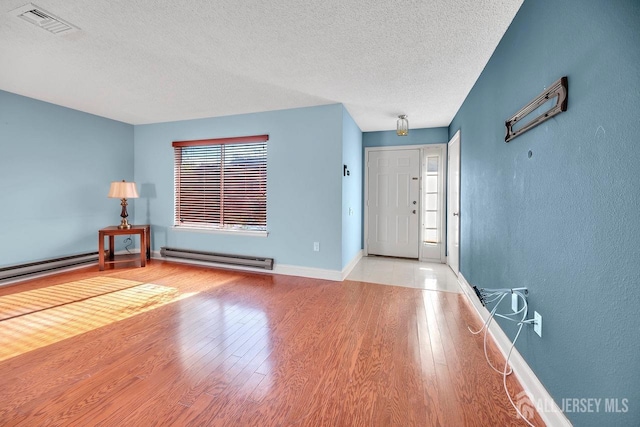 foyer entrance featuring a baseboard radiator, a textured ceiling, and light wood-type flooring