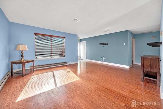 living room featuring hardwood / wood-style floors, a textured ceiling, and baseboard heating