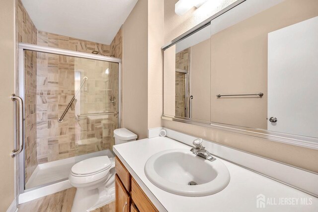 bathroom featuring vanity, toilet, and a shower with door