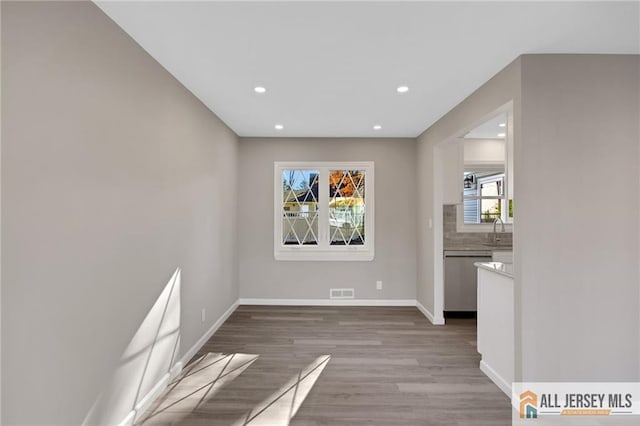 interior space with visible vents, a sink, baseboards, and wood finished floors