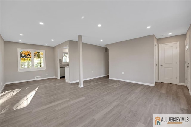 unfurnished living room with recessed lighting, visible vents, baseboards, and wood finished floors