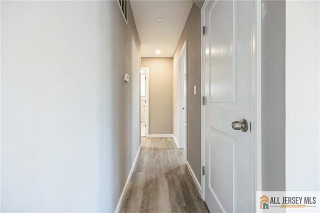 hall featuring wood finished floors, visible vents, and baseboards