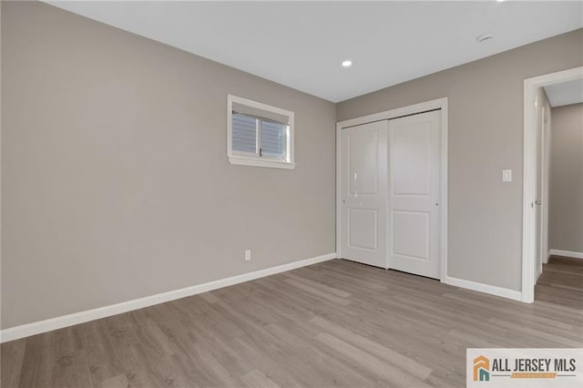 unfurnished bedroom with light wood finished floors, a closet, and baseboards