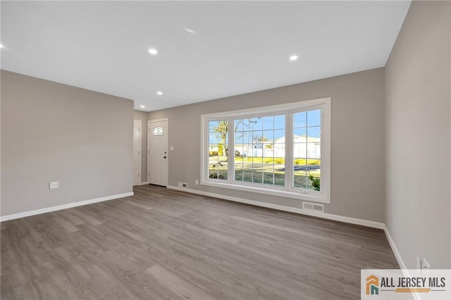 unfurnished room featuring baseboards, visible vents, wood finished floors, and recessed lighting