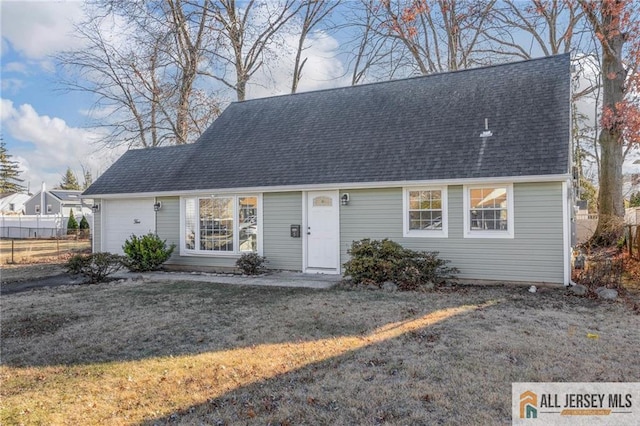 view of front of house with a shingled roof, an attached garage, and a front yard