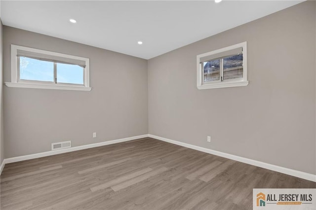 empty room with recessed lighting, wood finished floors, visible vents, and baseboards