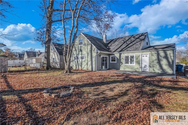 view of front of house with fence, a chimney, and a patio