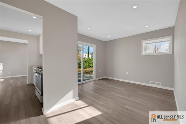 spare room with baseboards, visible vents, wood finished floors, and recessed lighting