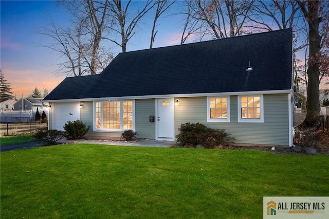 view of front of property featuring a shingled roof and a yard