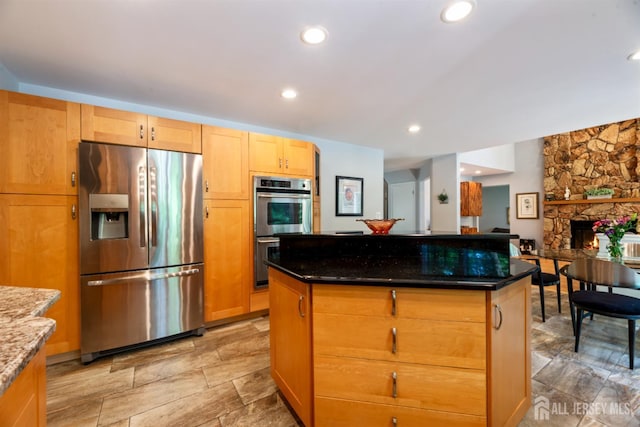 17 Theodore Dr, East Brunswick, NJ 08816 - kitchen featuring stainless steel appliances, dark stone countertops, a stone fireplace, a center island, and light stone finish floors