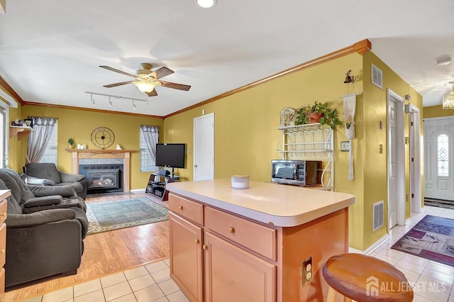 kitchen featuring ornamental molding, a center island, light tile patterned floors, ceiling fan, and track lighting