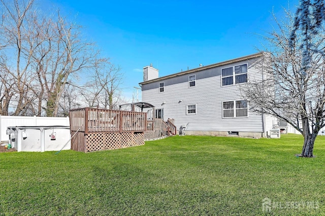 rear view of property featuring a pool side deck and a lawn