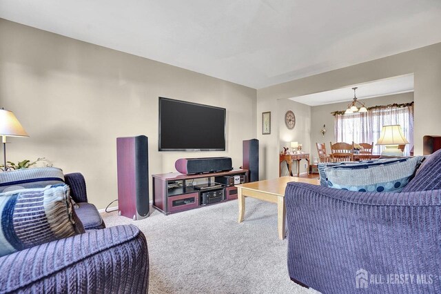 carpeted living room with an inviting chandelier