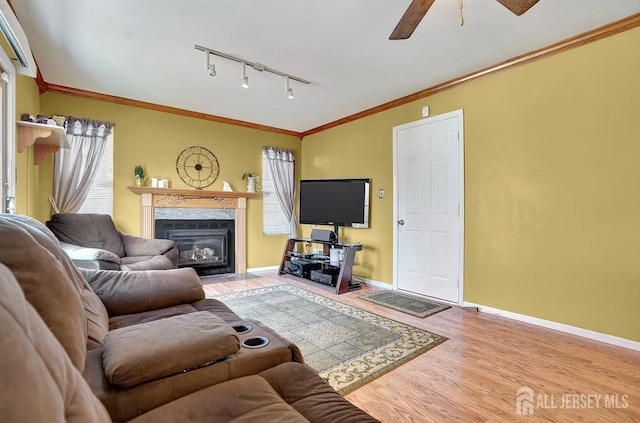 living room with crown molding, a healthy amount of sunlight, a premium fireplace, and hardwood / wood-style floors