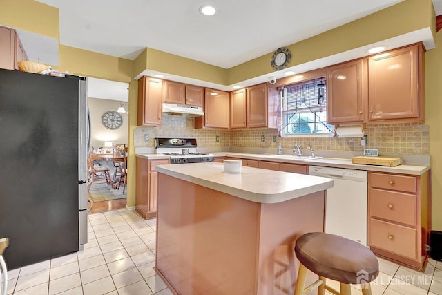 kitchen with sink, white appliances, a breakfast bar area, a center island, and decorative backsplash