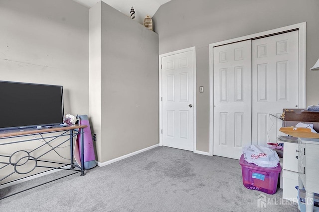 bedroom featuring lofted ceiling, a closet, light colored carpet, and baseboards