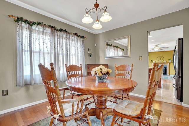 dining room featuring ceiling fan with notable chandelier and light wood-type flooring