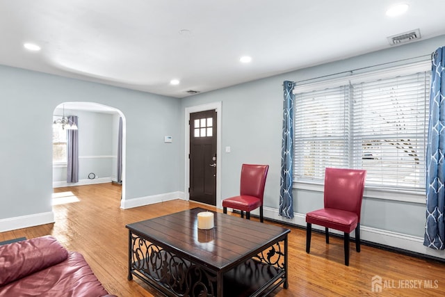 living area with arched walkways, recessed lighting, wood finished floors, visible vents, and baseboards