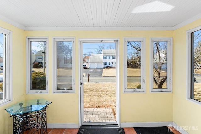 doorway to outside featuring crown molding, baseboards, tile patterned flooring, and a healthy amount of sunlight