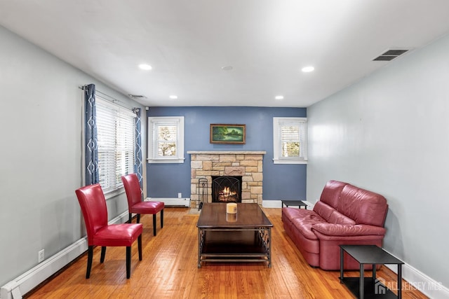 living room with baseboards, a baseboard radiator, wood finished floors, baseboard heating, and a fireplace