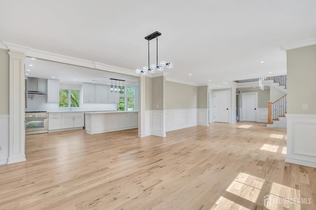 737 Wingate Dr, Bridgewater, NJ 08807 - unfurnished living room with ornamental molding, a decorative wall, a chandelier, wainscoting, and light wood-type flooring
