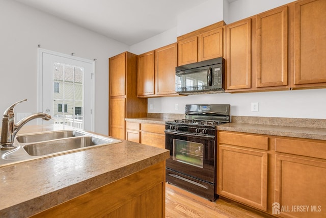 kitchen featuring black appliances, light wood-style floors, brown cabinets, and a sink