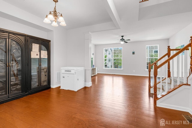 interior space featuring wood finished floors, stairs, ceiling fan with notable chandelier, baseboards, and visible vents