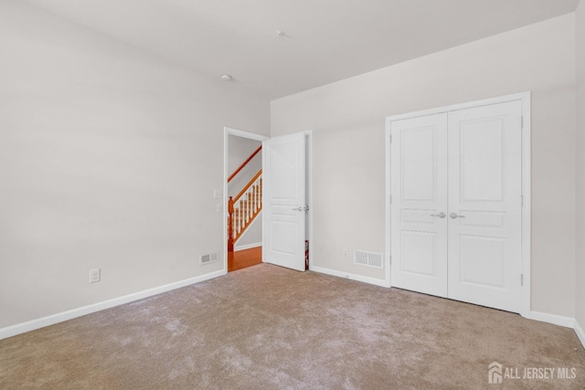 unfurnished bedroom featuring a closet, carpet flooring, baseboards, and visible vents