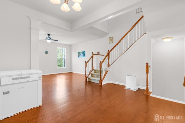 foyer entrance featuring baseboards, wood finished floors, ceiling fan with notable chandelier, and stairs