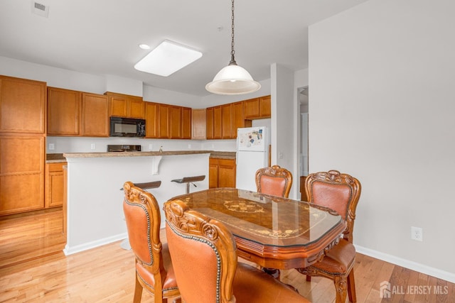 dining space with baseboards, visible vents, and light wood finished floors