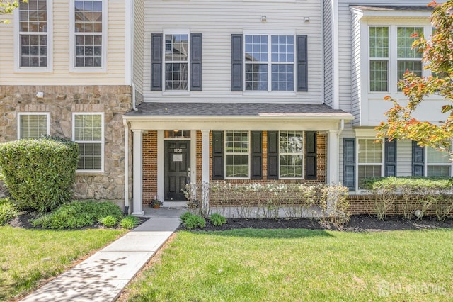 view of front of home with a porch, a front lawn, and stone siding