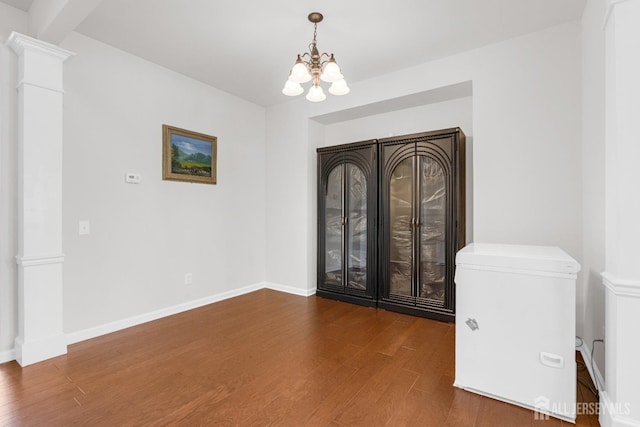entryway with baseboards, decorative columns, a notable chandelier, and dark wood-style flooring