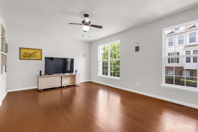 unfurnished living room with visible vents, a ceiling fan, dark wood-style floors, and baseboards