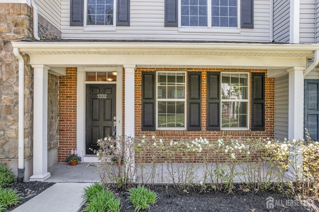 property entrance with stone siding, covered porch, and brick siding