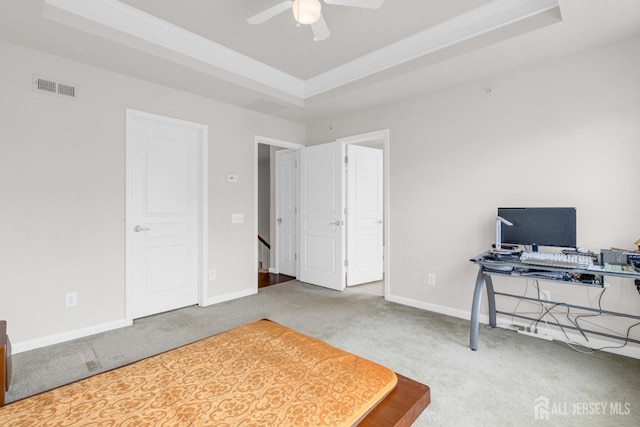 office space featuring carpet, visible vents, ceiling fan, and a tray ceiling