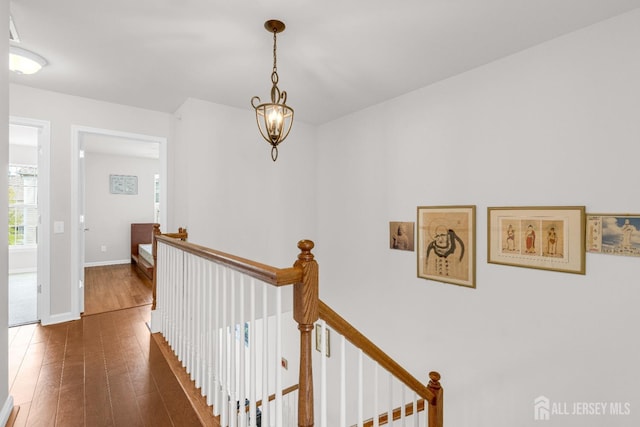 hallway with an upstairs landing, hardwood / wood-style floors, and baseboards