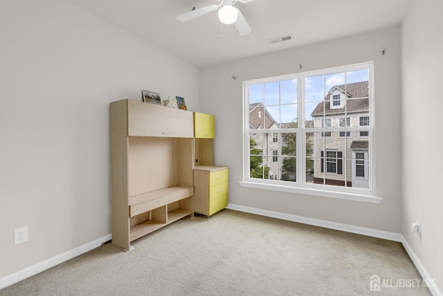 unfurnished bedroom featuring baseboards, visible vents, multiple windows, and light colored carpet