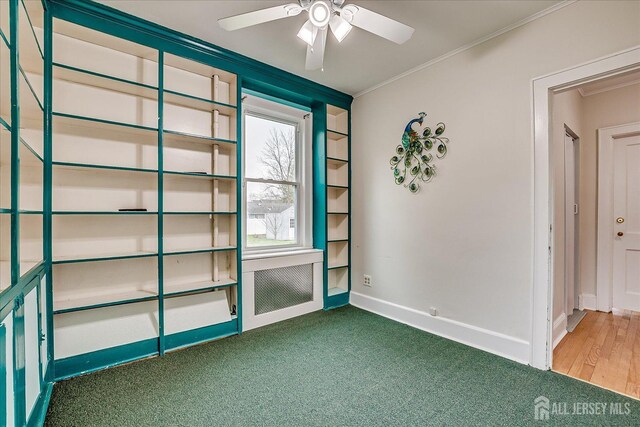 carpeted empty room with crown molding, a ceiling fan, and baseboards