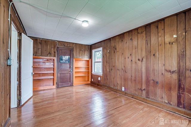 spare room featuring wood walls, wood finished floors, and baseboards