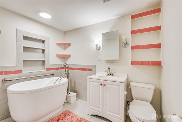 full bathroom featuring tile walls, a freestanding tub, toilet, tile patterned floors, and vanity