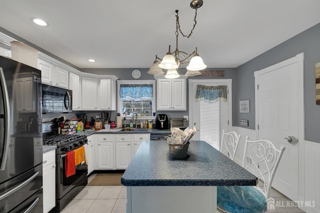 kitchen with a kitchen island, dark countertops, black appliances, and white cabinetry