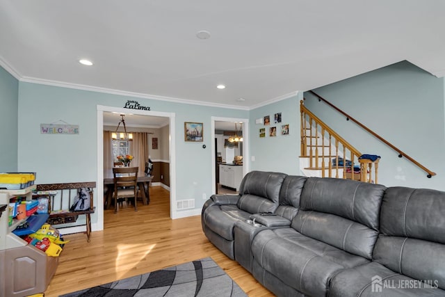 living area featuring light wood finished floors, stairway, crown molding, and an inviting chandelier