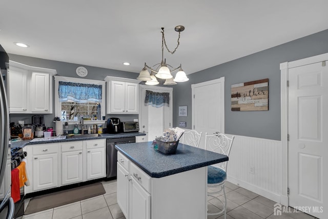 kitchen with range with gas stovetop, a wainscoted wall, white cabinets, dishwasher, and dark countertops