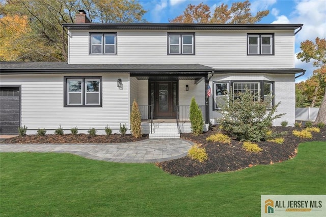 view of front property with covered porch, a front yard, and a garage