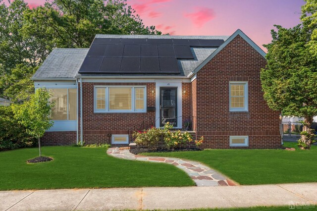 view of front of house featuring solar panels and a lawn