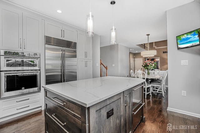 5 Bridle Ct, Monroe, NJ 08831 - kitchen with appliances with stainless steel finishes, dark wood-style flooring, a center island, light stone counters, and baseboards