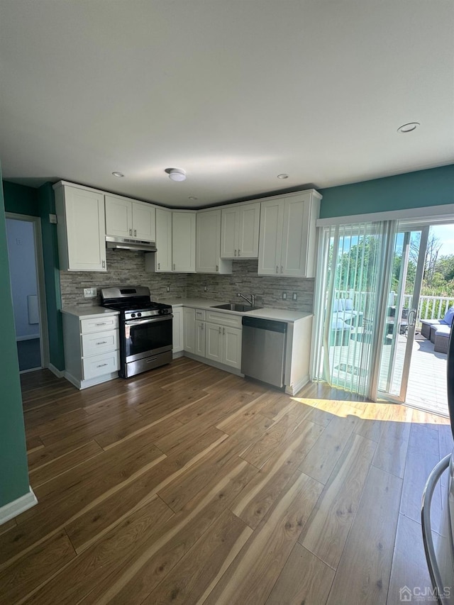 kitchen with dark wood-type flooring, sink, appliances with stainless steel finishes, decorative backsplash, and white cabinets