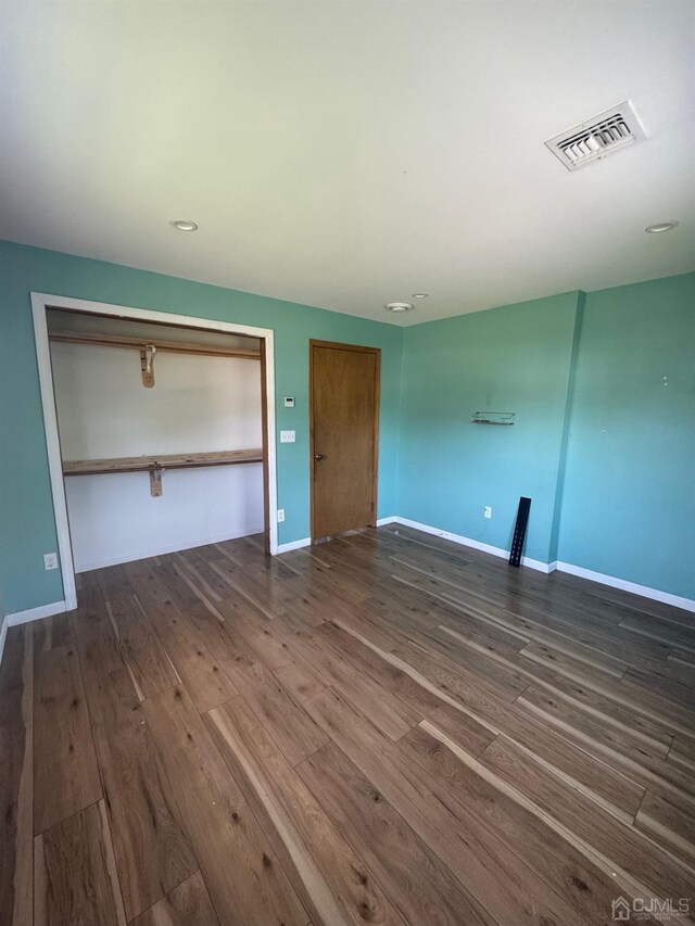 unfurnished bedroom with a closet and dark hardwood / wood-style floors